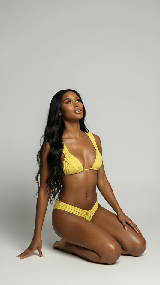 Woman wearing a yellow bikini sitting on a gray background